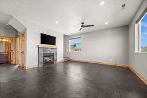 Unfurnished living room featuring a fireplace, recessed lighting, a textured ceiling, a ceiling fan, and concrete floors