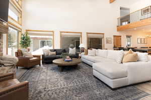 Living room with wood finished floors, a towering ceiling, and beamed ceiling