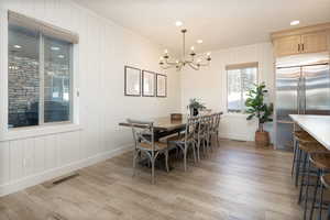 Dining area with recessed lighting, light wood finished floors, crown molding, a chandelier, and wood walls