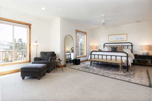 Carpeted bedroom with multiple windows, ceiling fan, and recessed lighting