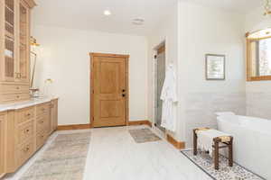 Full bathroom with vanity, a freestanding tub, a stall shower, recessed lighting, and light marble finish flooring