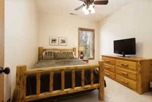 Bedroom with ceiling fan, a textured ceiling, and light carpet