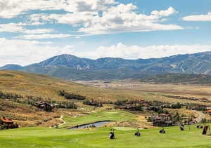 View of mountain backdrop with a nearby body of water and a golf club