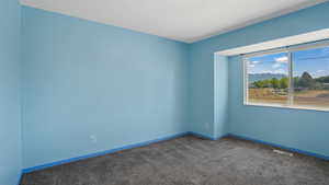 Carpeted empty room with a mountain view and baseboards