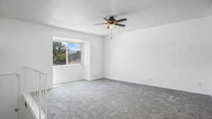 Carpeted empty room with ceiling fan and baseboards