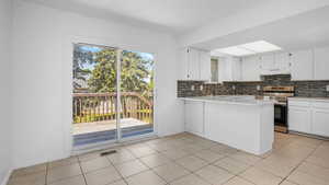 Kitchen featuring backsplash, white cabinetry, light tile patterned floors, electric stove, and light stone counters