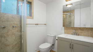 Full bath featuring vanity, a shower stall, and decorative backsplash