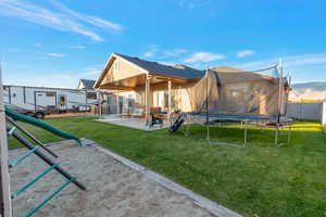 Back of house featuring a trampoline, a patio area, a playground, and stucco siding