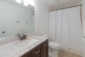 Full bathroom with vanity, shower / bath combination with curtain, and light tile patterned floors