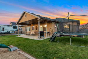 Back of house featuring a patio area, a trampoline, and stucco siding