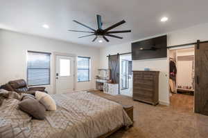 Bedroom with a barn door, carpet flooring, recessed lighting, a walk in closet, and ceiling fan