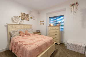 Bedroom with dark colored carpet and baseboards