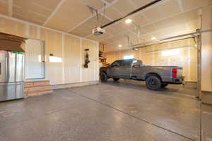 Garage featuring freestanding refrigerator and a garage door opener