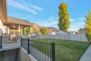 Fenced backyard featuring a playground, a mountain view, and a patio area