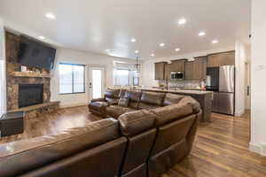 Living room featuring recessed lighting, dark wood-style floors, and a stone fireplace