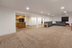 Living area with light carpet and recessed lighting