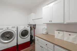 Laundry area with dark wood-style floors, cabinet space, and separate washer and dryer