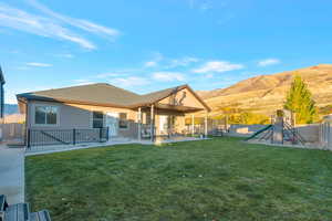Rear view of house with a patio area, a fenced backyard, a mountain view, a playground, and a trampoline