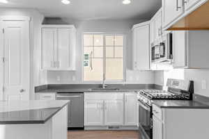 Kitchen with stainless steel appliances, white cabinets, recessed lighting, and light wood-type flooring