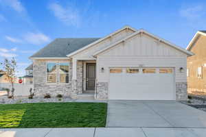 Craftsman-style home with board and batten siding, driveway, stone siding, an attached garage, and a shingled roof