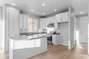 Kitchen featuring appliances with stainless steel finishes, white cabinetry, light wood finished floors, and recessed lighting
