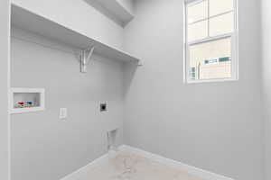 Laundry room with hookup for an electric dryer, hookup for a washing machine, and light marble finish floors