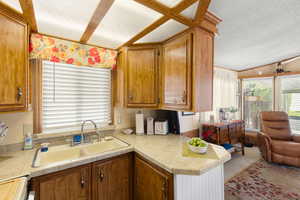Kitchen featuring a textured ceiling, brown cabinetry, open floor plan, a peninsula, and vaulted ceiling