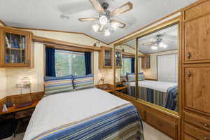 Bedroom with vaulted ceiling, a textured ceiling, ceiling fan, a closet, and ornamental molding