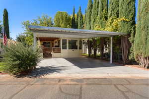 View of front of property with covered porch, concrete driveway, and an attached carport