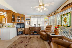 Sitting room featuring a textured ceiling, light carpet, a ceiling fan, wainscoting, and crown molding