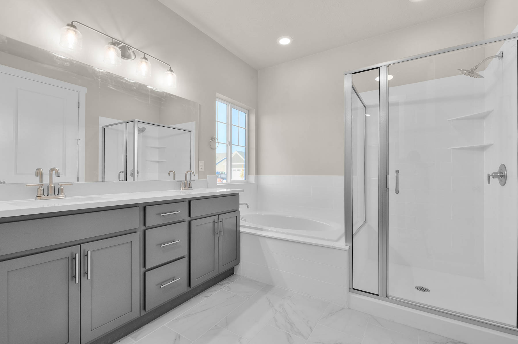 Bathroom featuring double vanity, a garden tub, a shower stall, light marble finish floors, and recessed lighting