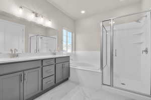 Bathroom featuring double vanity, a garden tub, a shower stall, light marble finish floors, and recessed lighting