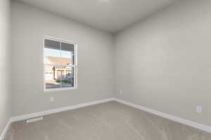 Carpeted spare room featuring baseboards