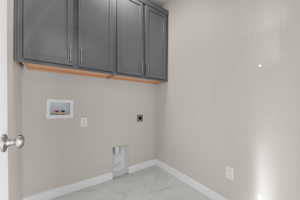 Laundry room featuring light marble finish floors, electric dryer hookup, hookup for a washing machine, and cabinet space
