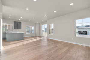 Unfurnished living room with recessed lighting, plenty of natural light, and light wood-style flooring