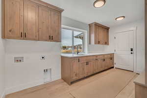Laundry room featuring cabinet space, electric dryer hookup, light wood finished floors, and hookup for a washing machine