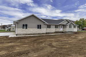 Craftsman inspired home featuring stone siding, board and batten siding, and roof with shingles
