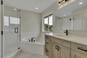 Bathroom featuring a bath, a shower stall, vanity, recessed lighting, and light marble finish flooring
