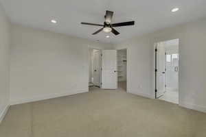 Unfurnished bedroom with light colored carpet, a spacious closet, recessed lighting, a ceiling fan, and ensuite bath