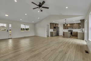 Unfurnished living room featuring vaulted ceiling, light wood-style flooring, recessed lighting, and a ceiling fan