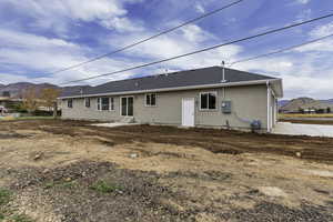 Rear view of property featuring a mountain view, a shingled roof, and stucco siding