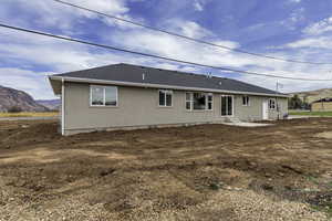 Rear view of property with a mountain view, a patio, and a shingled roof