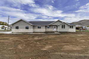 Ranch-style home featuring stone siding, board and batten siding, roof with shingles, and a mountain view