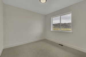 Carpeted empty room featuring baseboards and a mountain view