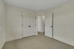 Unfurnished bedroom featuring light carpet and a closet