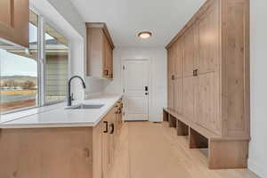 Mudroom with light wood finished floors and a sink
