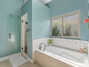Bathroom with a shower stall, jetted tub, and tile patterned flooring