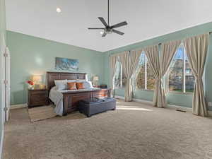 Carpeted primary bedroom featuring ceiling fan, recessed lighting, & vaulted ceilings