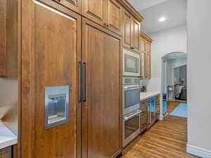 Kitchen with Thermador built-in refrigerator, hardwood floors, & recessed lighting.
