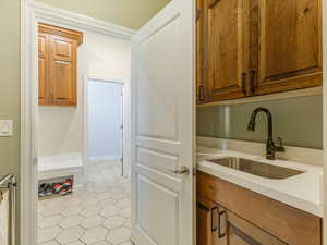Laundry area featuring a sink, tile floors, and cabinets